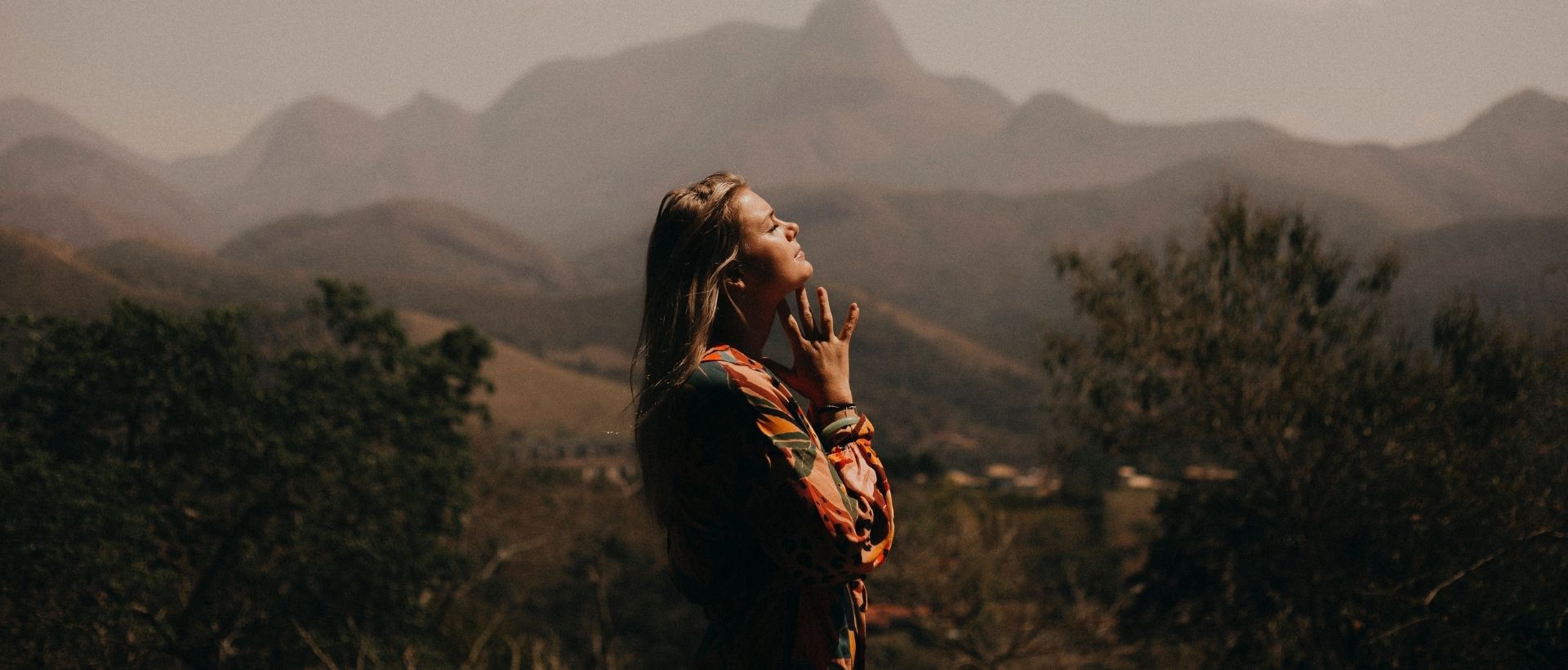 a woman standing in front of a mountain range.