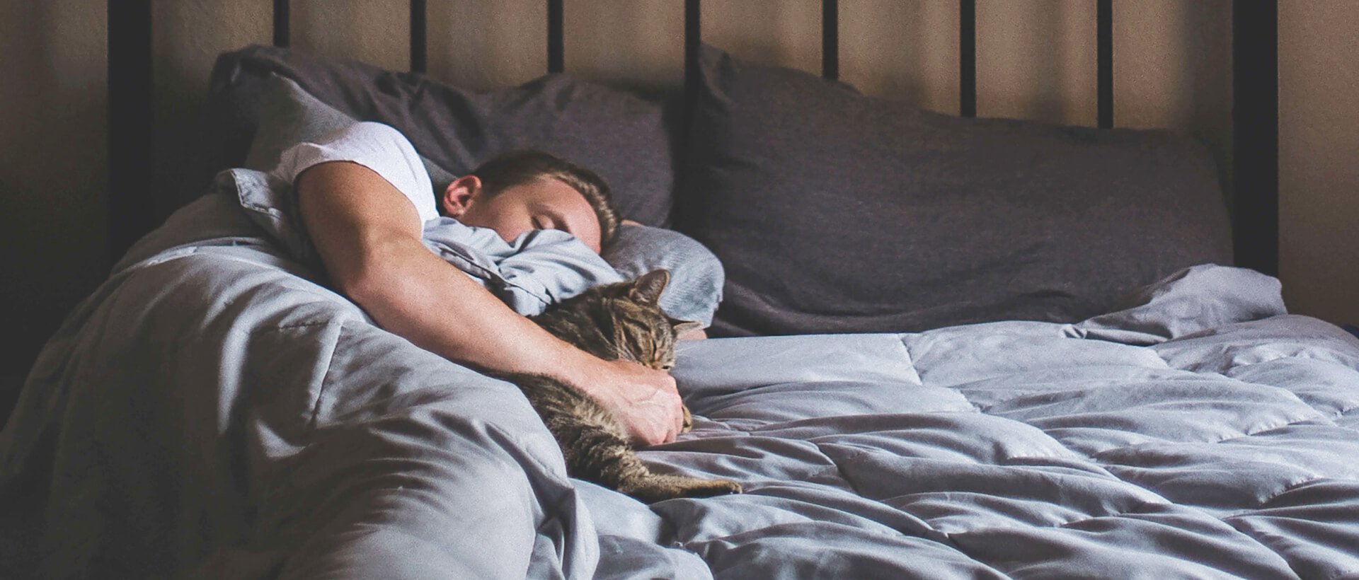 a man sleeping in bed with his cat.