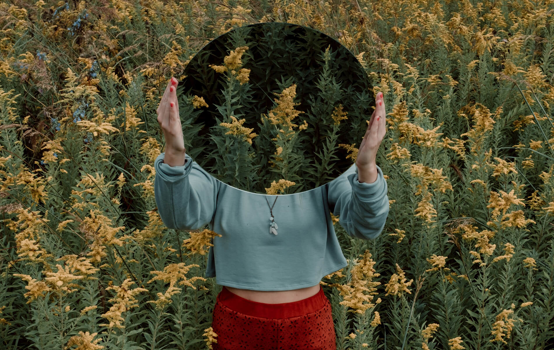 a woman standing in a field with her hands in the air.