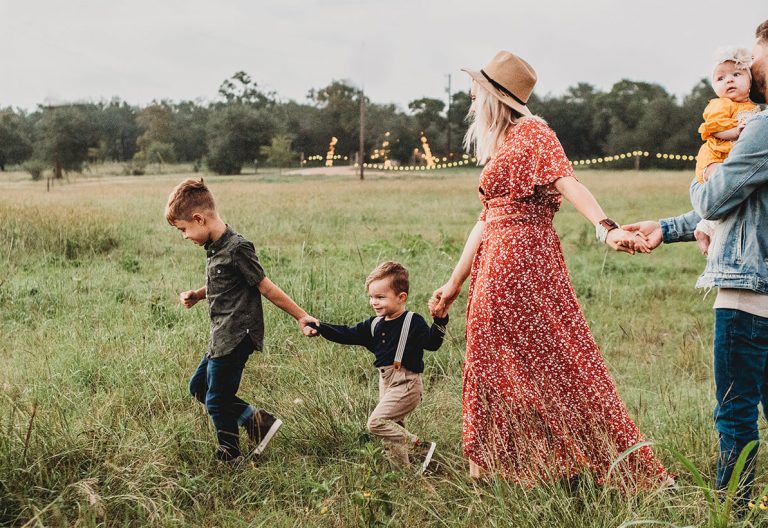 a family walking through a field holding hands.