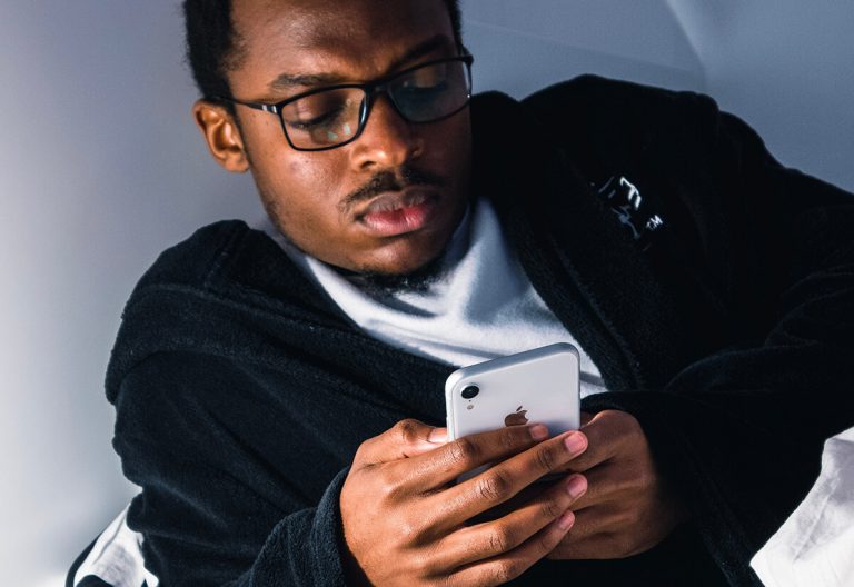 a man in glasses looking at a cell phone.