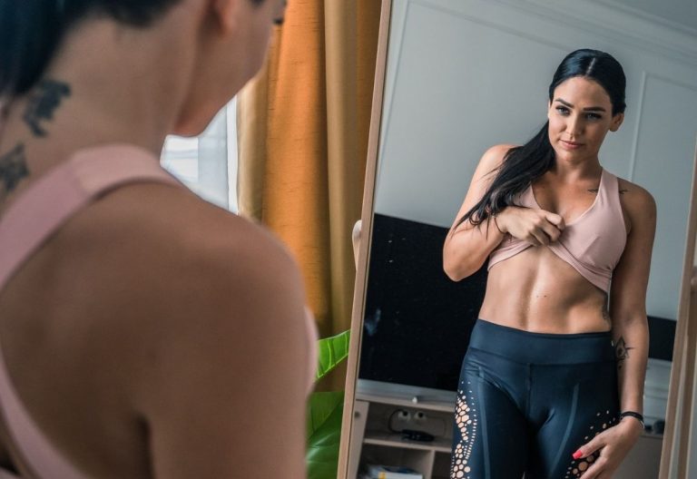 a woman standing in front of a mirror brushing her teeth.