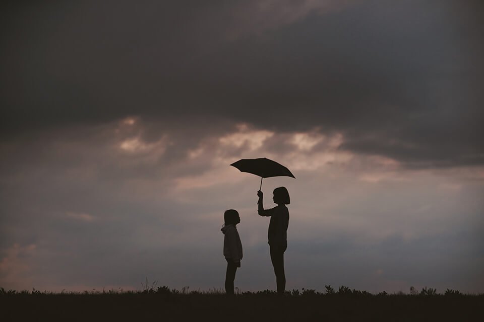 Woman holding out umbrella for child