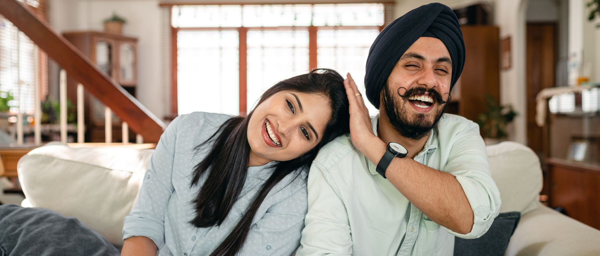 a man and a woman sitting on a couch smiling.