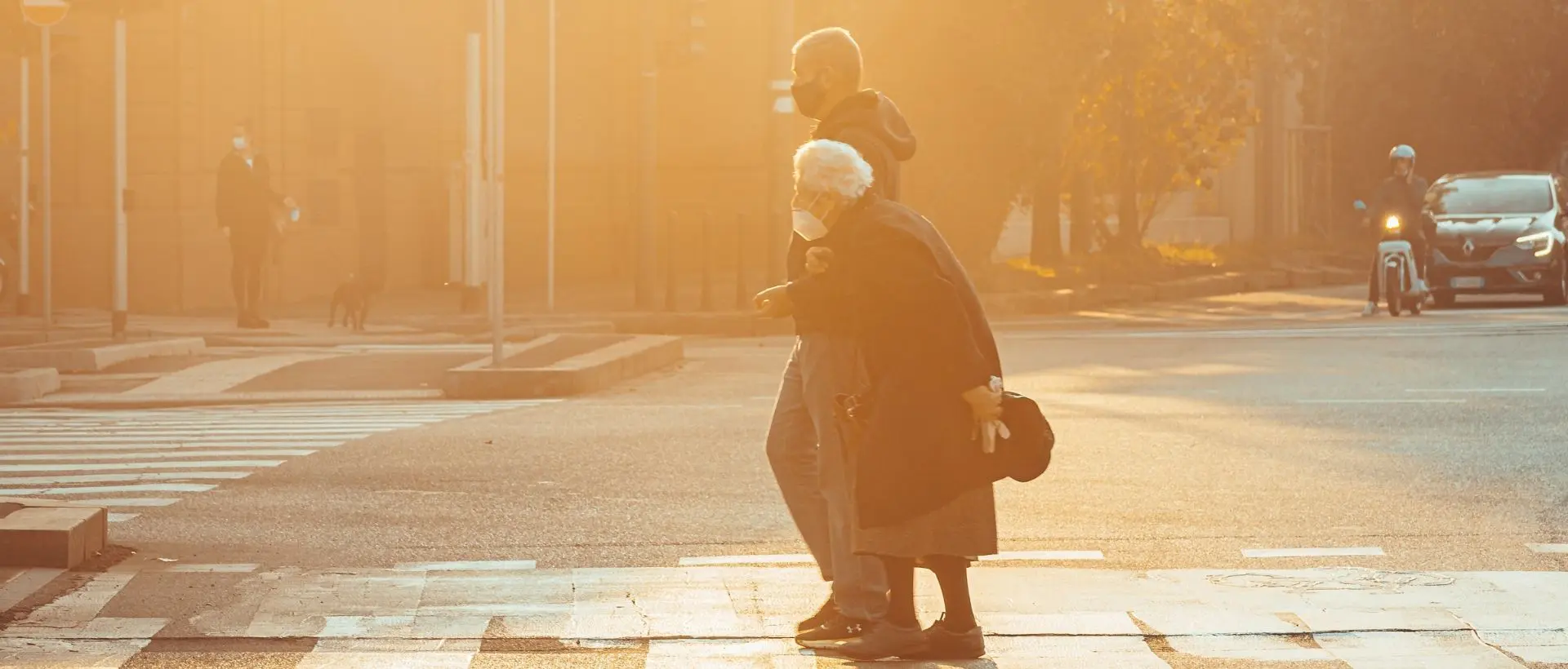 a woman with a child on her back crossing a street.