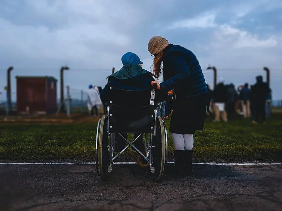 Woman helping elderly man in wheelchair