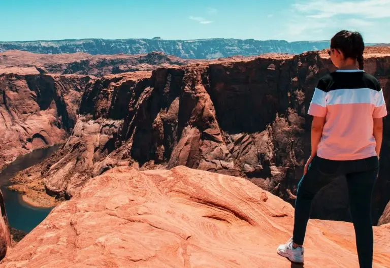 a woman standing on top of a cliff overlooking a canyon.