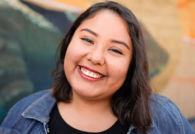 a woman smiling in front of a painting.