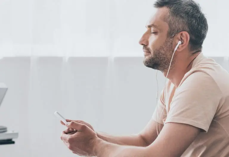 a man sitting on a couch looking at his cell phone.