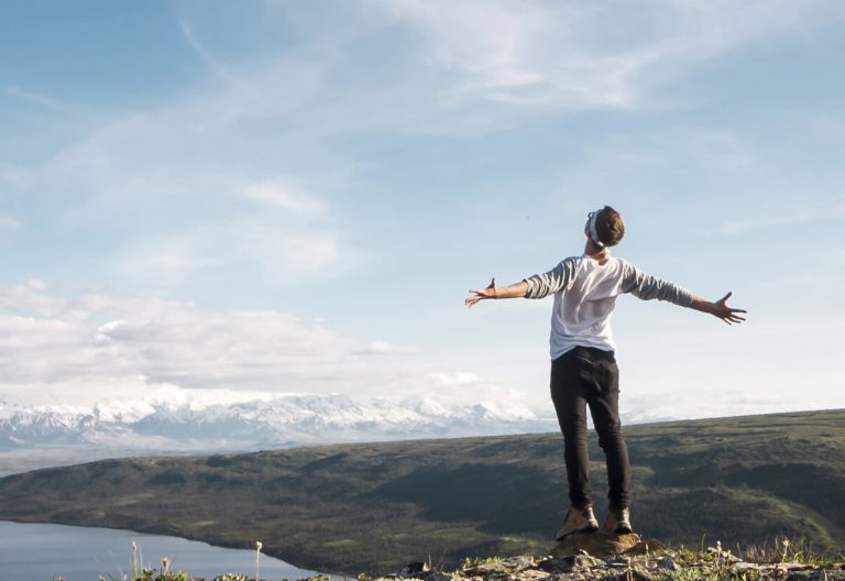 a man standing on top of a hill with his arms outstretched.