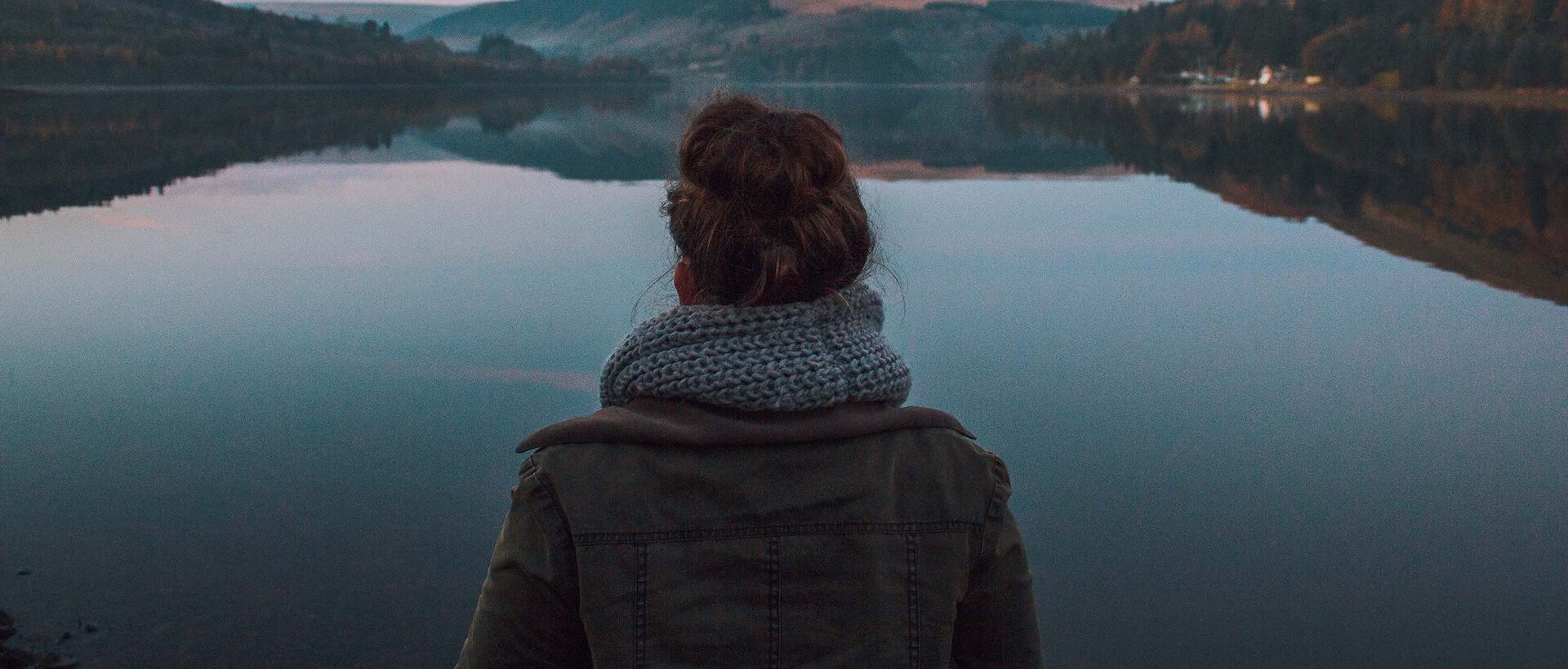 a woman standing in front of a body of water.