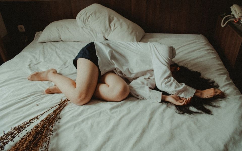 a woman laying on a bed with her legs spread out.