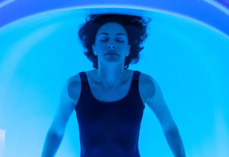 a woman in a black tank top floating in a blue tube.