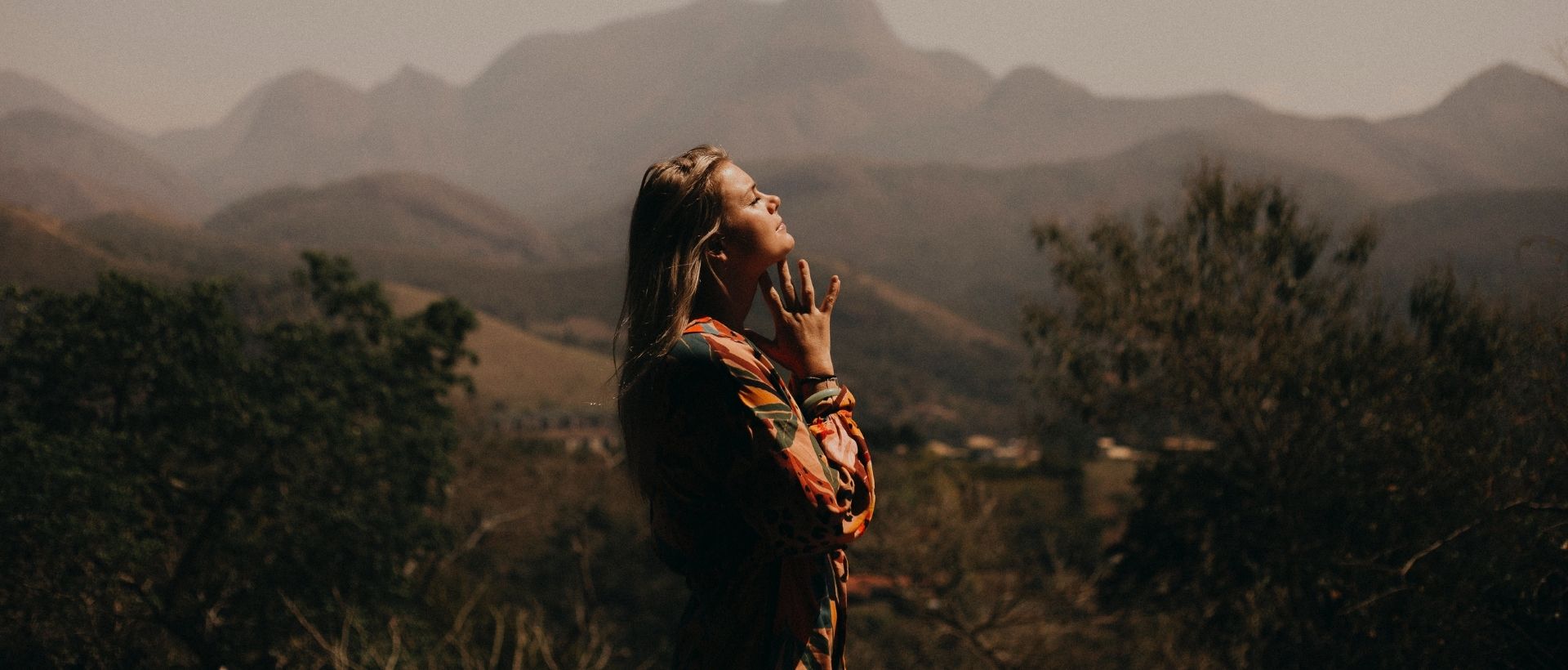 a woman standing in the mountains talking on a cell phone.