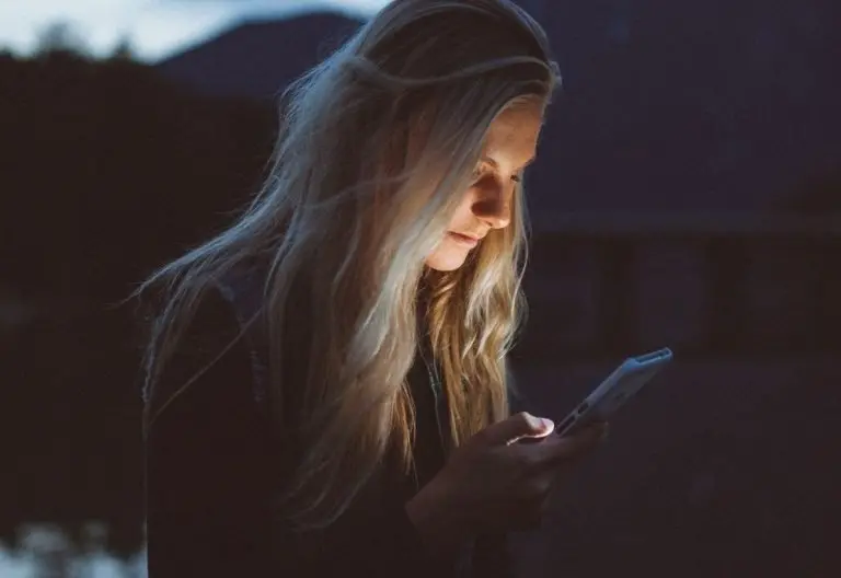 a woman looking at her cell phone in the dark.