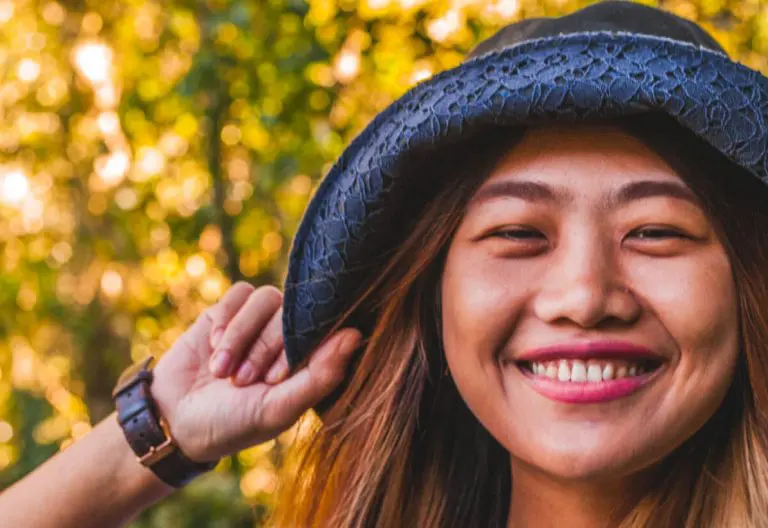 a woman wearing a hat and smiling for the camera.